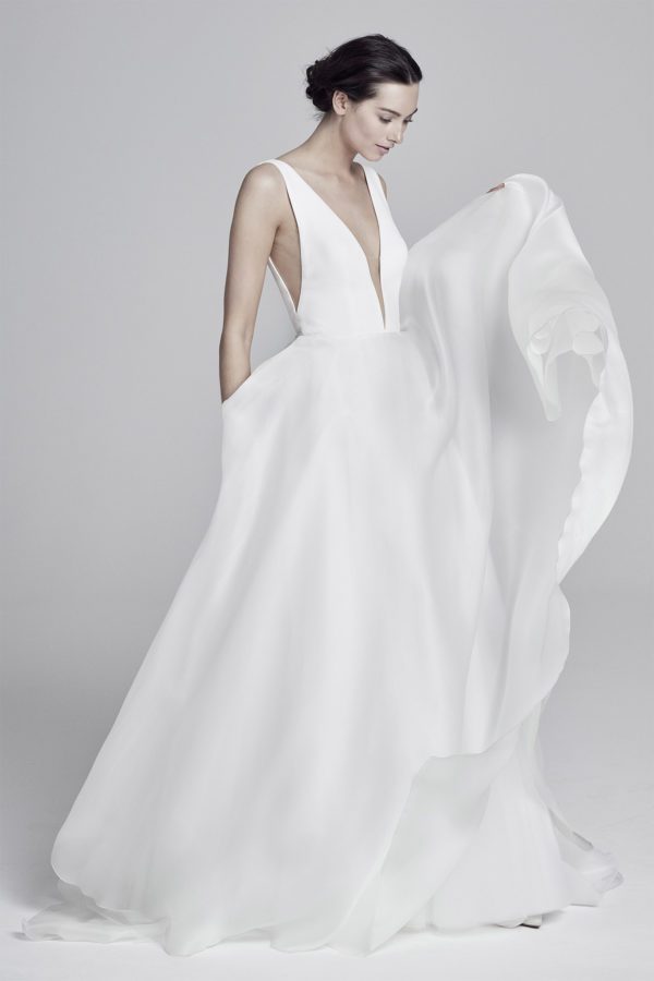 Suzanne Neville Serrano Wedding Dress - Flowing A Line dress in elegant crepe fabric with deep plunging v-neckline and side sexy cut on bodice.