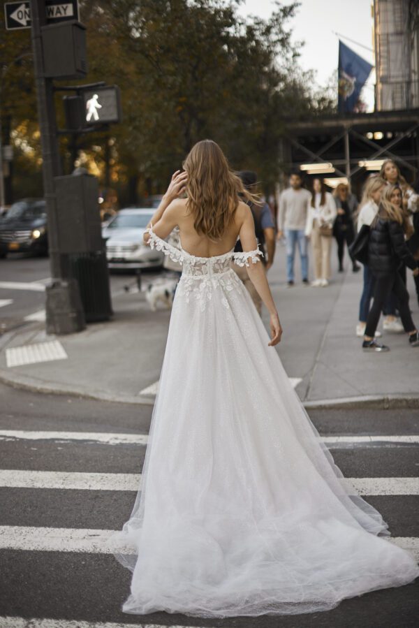 Netta BenShabu Sylvie Wedding Dress - A-line tulle gown featuring floral applique throughout the bodice with off the shoulder straps and front slit skirt.