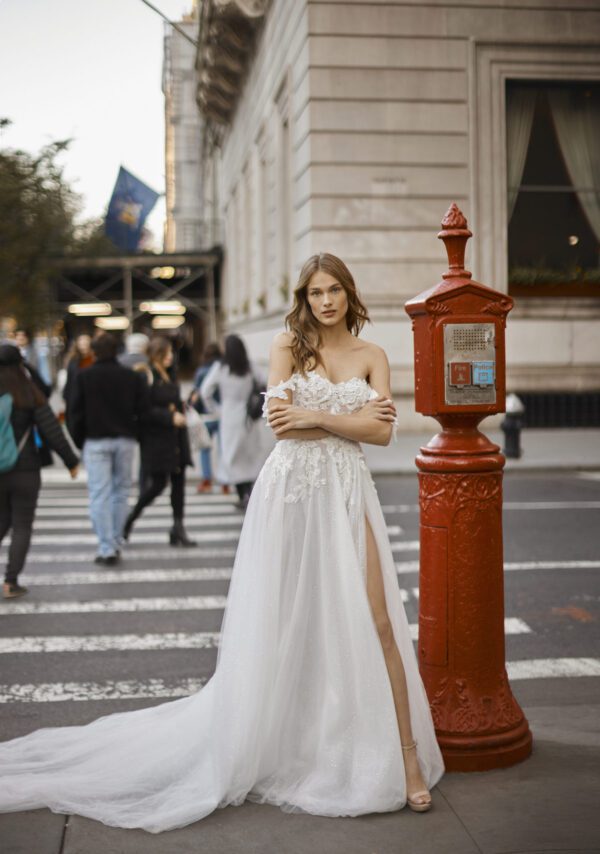 Netta BenShabu Sylvie Wedding Dress - A-line tulle gown featuring floral applique throughout the bodice with off the shoulder straps and front slit skirt.