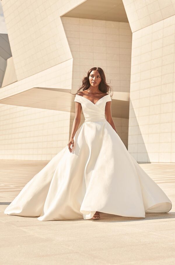 Paloma Blanca 4977 Wedding Dress - A line silhouette with draped Mikado fabric, off the shoulder bodice, covered buttons, full circle skirt with pockets.
