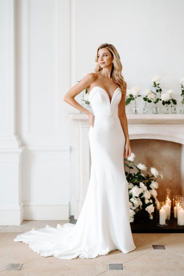 Suzanne Neville Corinthia Wedding Dress - Corinthia features a structured sweetheart neckline with deep v cleavage, a thin belt detail which sits above a fit-to-flare skirt.