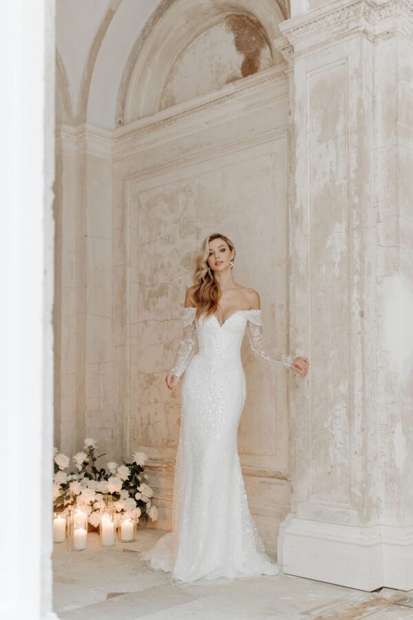 Suzanne Neville Excelsior Wedding Dress - Fitted bodice with an intricate embellished appliqué top to bottom, plunge neckline, and detachable long sleeves.