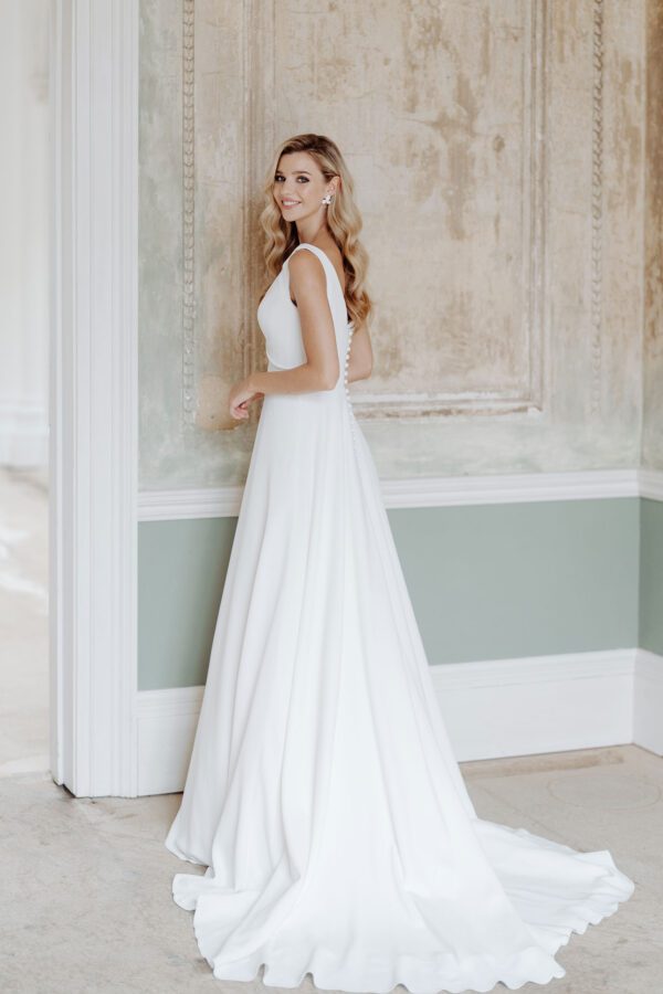 Suzanne Neville Lanesborough Wedding Dress - Flattering A Line silhouette, scoop neckline, fitted bodice, and draped detail, made of Italian crepe.