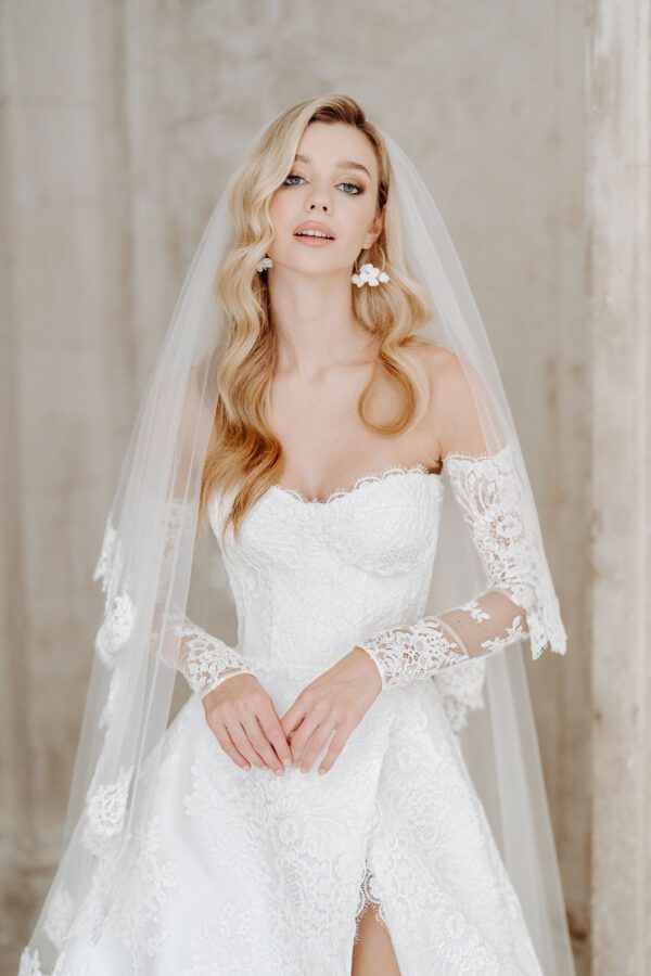 Suzanne Neville Wellesley Wedding Dress - Modifies A Line dress with a sweetheart neckline, illusion lace off the shoulder detachable sleeves, open slit on front and fitted corset bodice. 