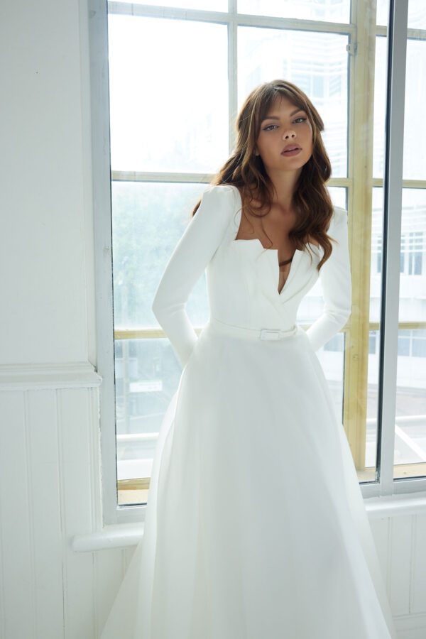 Suzanne Neville Conrad Wedding Dress - A-Line, striking neckline, V plunge, framed with long sleeves. Front