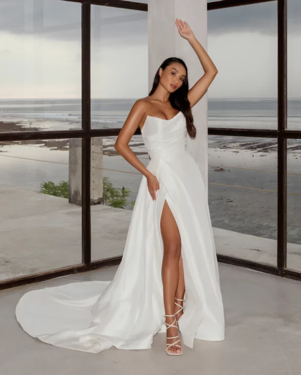 Tulle NY MP Satin Wedding Dress - Light Silk Satin strapless gown with a cat eye neckline, bias placed tucks, and a pleated skirt opening to a deep slit.