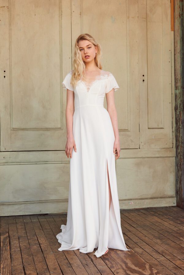 Christos Maven T402 Wedding Dress Sample Sale - A daring slit and deep V neckline on a Chantilly lace and crepe gown with fluttering sleeves.