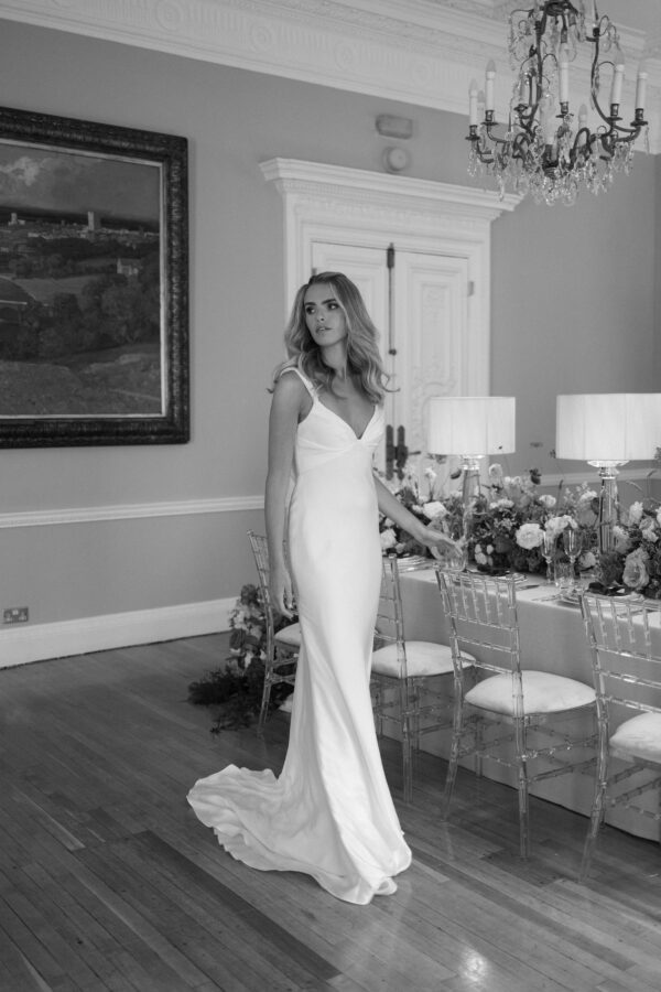 Suzanne Neville Zimmer Wedding Dress - Fit and flare dress with a structured draped bodice, straps, low open back with criss cross end and train.