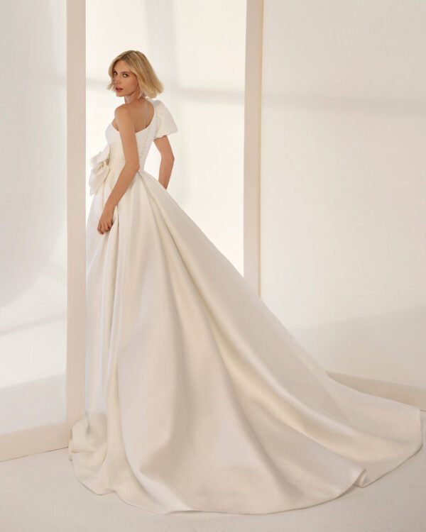 Rosa Clará Enio Wedding Dress - Princess-style Ballgown with draped and asymmetrical bodice, one puffed sleeve, and skirt with pleats at the waist.