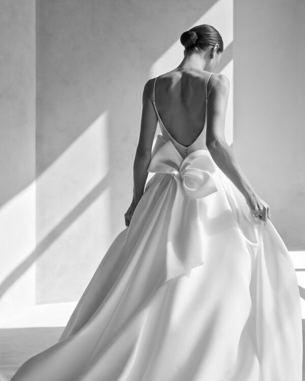 Rosa Clará Fabila Wedding Dress - A Line with a straight cut featuring a deep neckline, open back, and straps. Removable skirt with side slit.