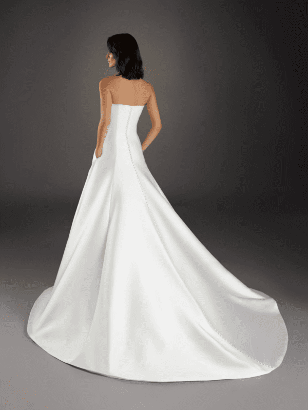 Pronovias Sagrada Wedding Dress - Fit and flare style dress with a strapless v-neckline, open back, covered buttons throughout the skirt and cape.