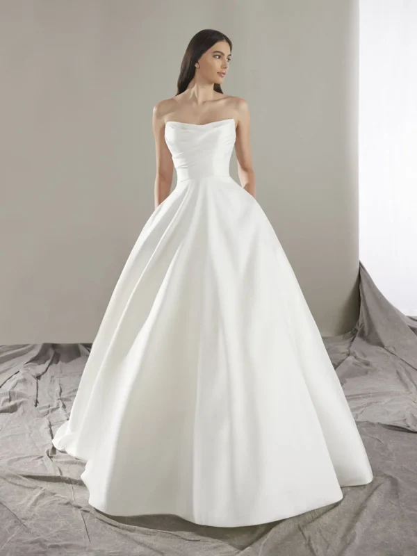 Pronovias Keoni Wedding Dress - Princess-cut with flattering pleats, Mikado fabric, sweetheart neckline, pockets details, wide train and open back.