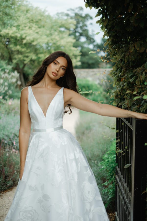 Suzanne Neville Willow Wedding Dress - A Line style dress with a beautiful floral fabric, a low plunging v neckline, ribbon belt detail and, fitted bodice.