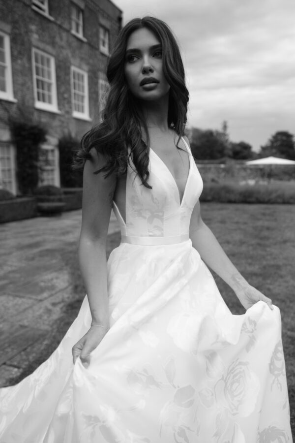 Suzanne Neville Willow Wedding Dress - A Line style dress with a beautiful floral fabric, a low plunging v neckline, ribbon belt detail and, fitted bodice.