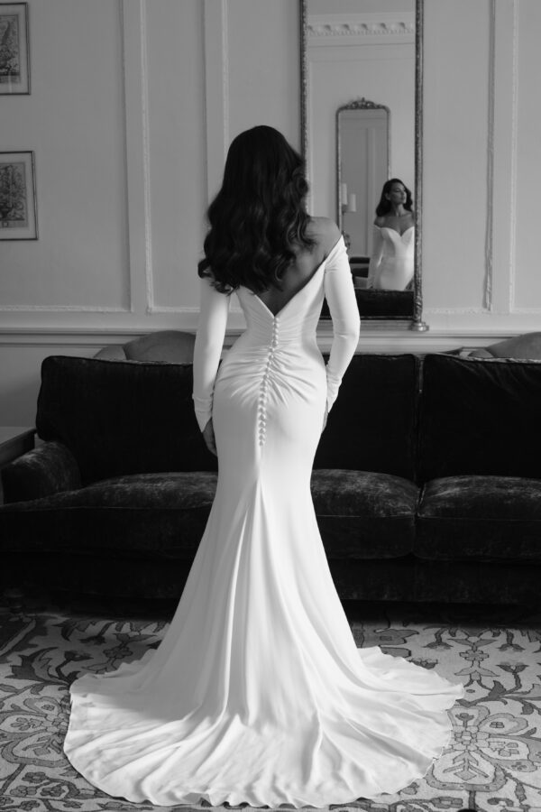 Suzanne Neville Dehlia Wedding Dress - Fit and flare style dress with a beautiful minimal and timeless look, featuring off the shoulder long sleeves, sweetheart neckline, low V-back, ruched detail in back. 