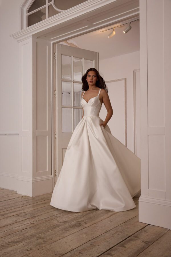 Suzanne Neville Mistletoe Wedding Dress - A-Line style dress with corset style bodice, skirt details, sweetheart neckline, side pockets, spaghetti straps, low back and covered buttons. 