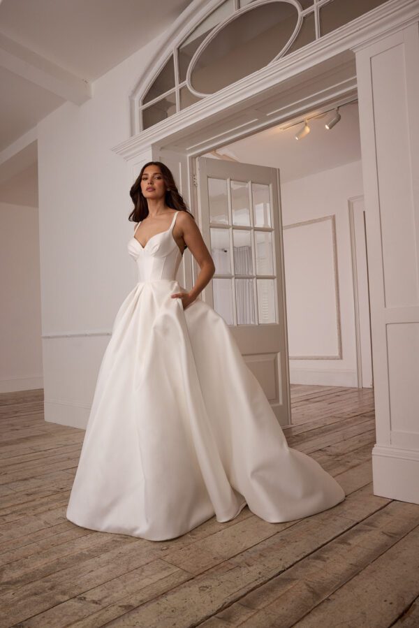 Suzanne Neville Mistletoe Wedding Dress - A-Line style dress with corset style bodice, skirt details, sweetheart neckline, side pockets, spaghetti straps, low back and covered buttons. 