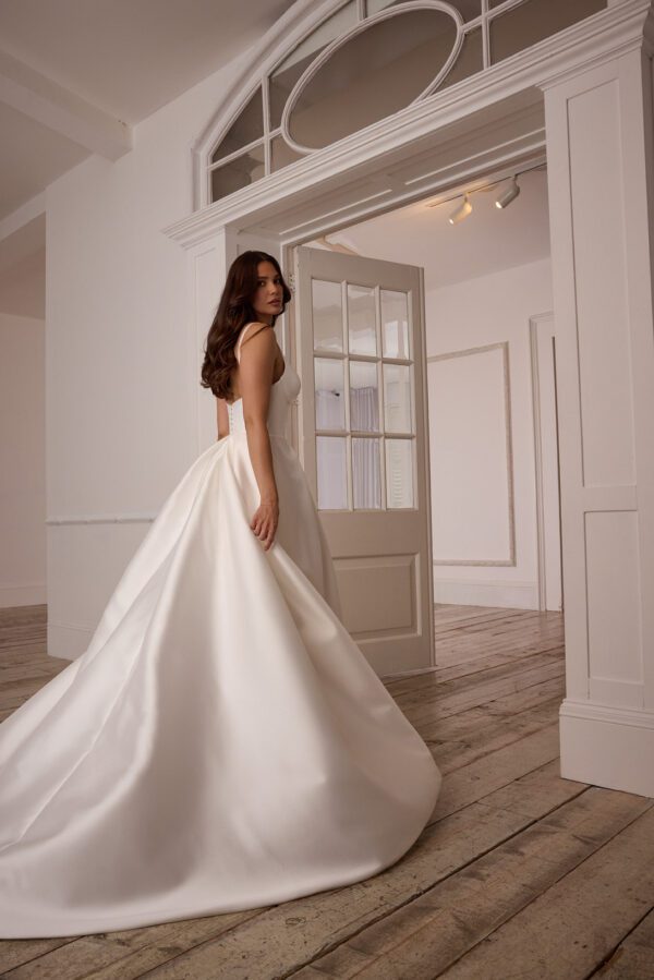 Suzanne Neville Mistletoe Wedding Dress - A-Line style dress with corset style bodice, skirt details, sweetheart neckline, side pockets, spaghetti straps, low back and covered buttons. 