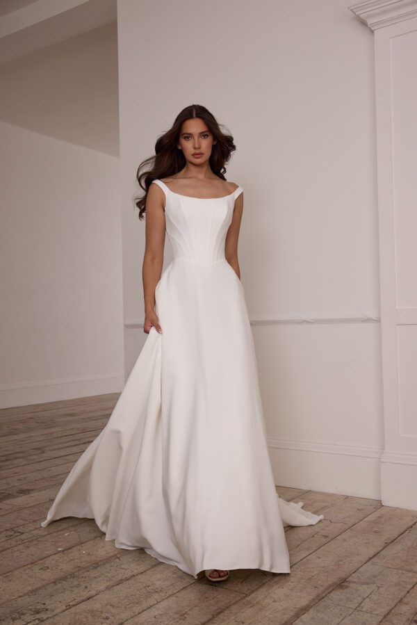 Suzanne Neville Fittonia Wedding Dress - A-Line style dress with low v waist, fitted corset bodice, bateau neckline, low v-back and covered buttons.