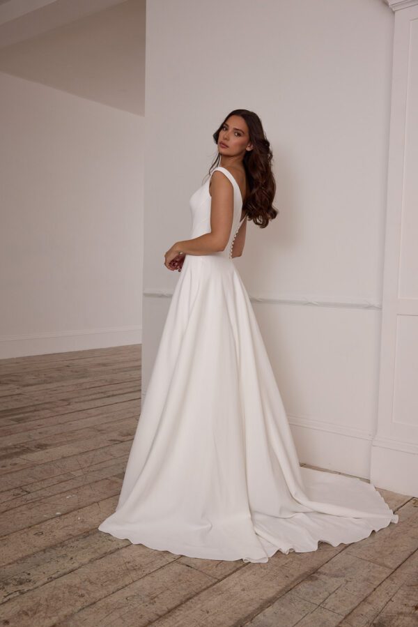 Suzanne Neville Fittonia Wedding Dress - A-Line style dress with low v waist, fitted corset bodice, bateau neckline, low v-back and covered buttons.