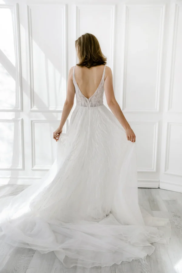 Enaura Margo Wedding Dress - A Line style dress adorned in pearls and glittering beads features a V-neck, V-back, and flowy tulle skirt.