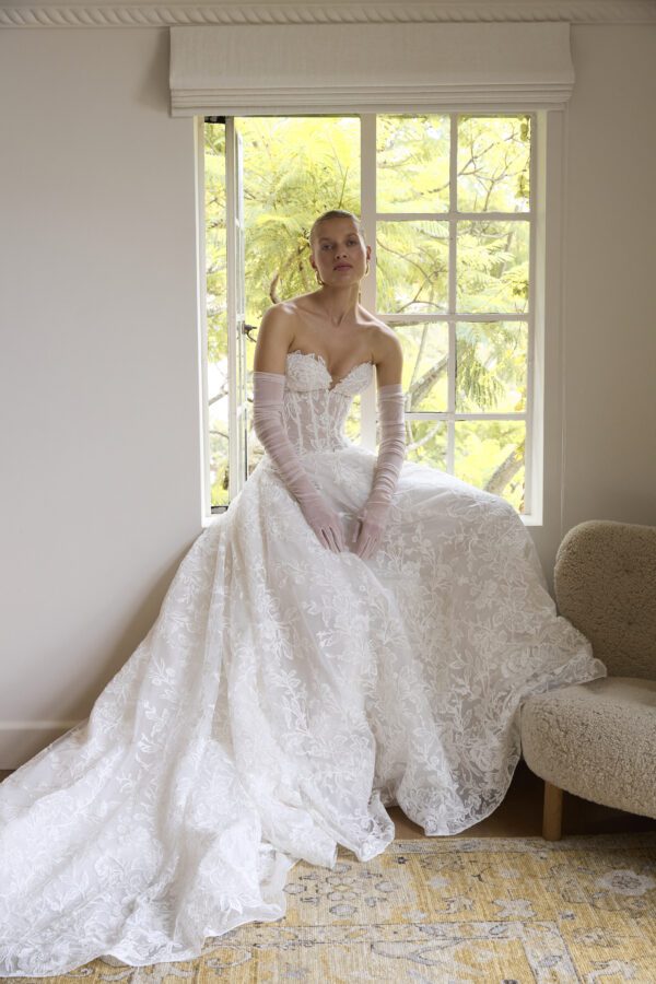 La Premiere Blossom Wedding Dress - A - Line style dress with sweetheart neckline, hand-placed floral appliqués, exposed boning bodice and long sleeves.