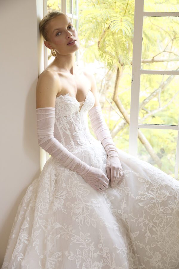 La Premiere Blossom Wedding Dress - A - Line style dress with sweetheart neckline, hand-placed floral appliqués, exposed boning bodice and long sleeves.