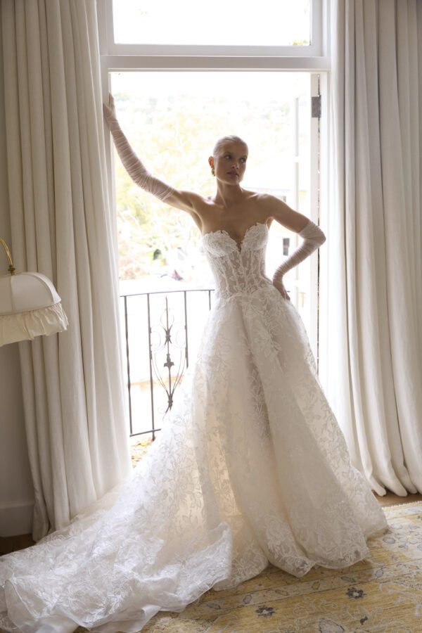La Premiere Blossom Wedding Dress - A - Line style dress with sweetheart neckline, hand-placed floral appliqués, exposed boning bodice and long sleeves.